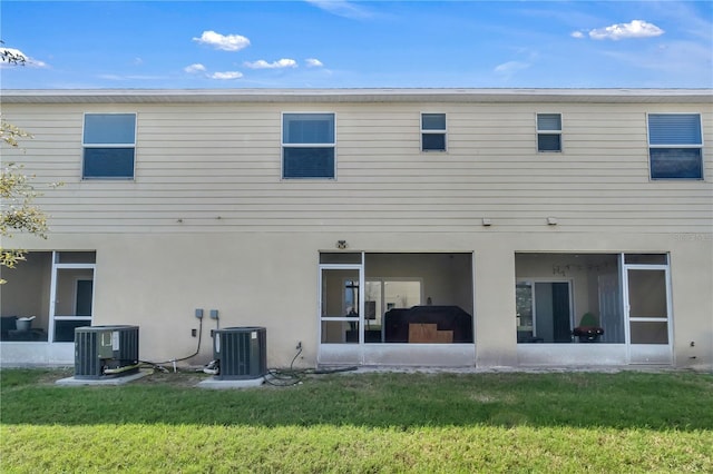 rear view of property with a yard, central AC, and a sunroom