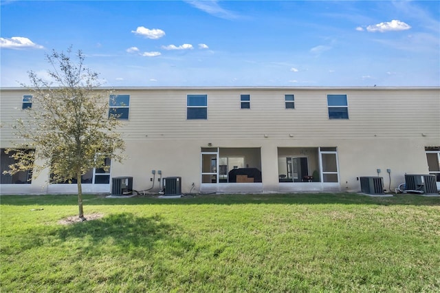 back of property with central air condition unit and a lawn