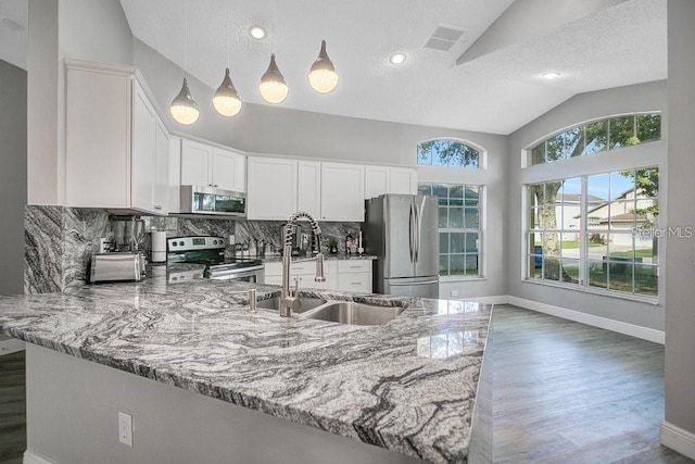 kitchen featuring lofted ceiling, sink, stainless steel appliances, light stone countertops, and white cabinets