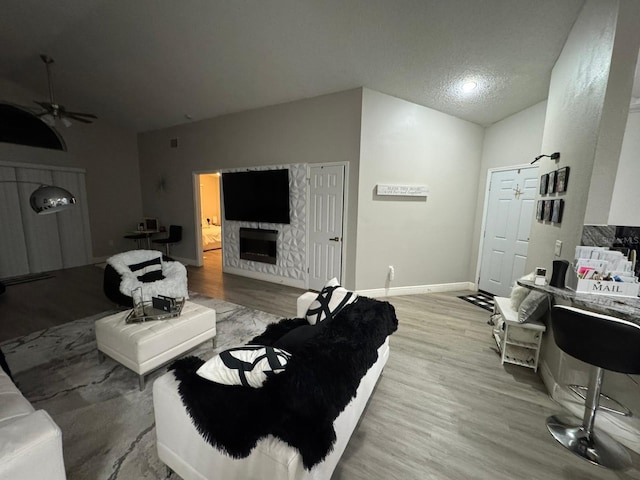 living room with ceiling fan, vaulted ceiling, and light wood-type flooring