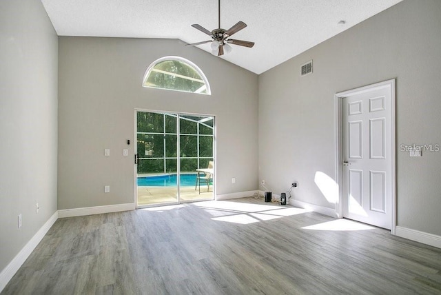 empty room with lofted ceiling, a textured ceiling, light hardwood / wood-style flooring, and ceiling fan