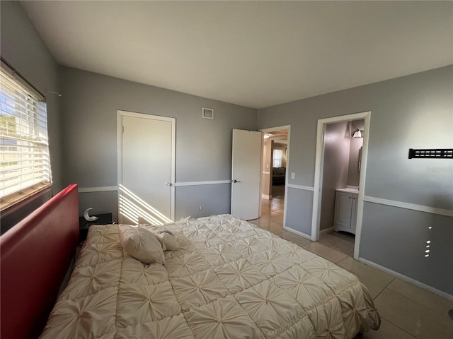 bedroom with light tile patterned flooring and ensuite bath