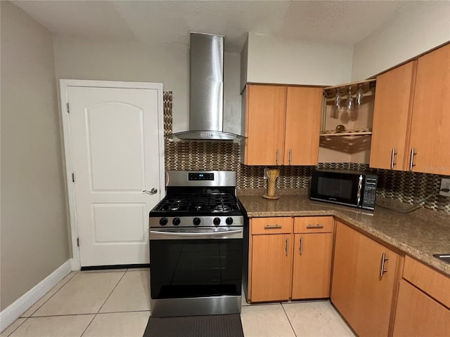 kitchen featuring light tile patterned floors, dark stone countertops, stainless steel range with gas stovetop, tasteful backsplash, and wall chimney exhaust hood