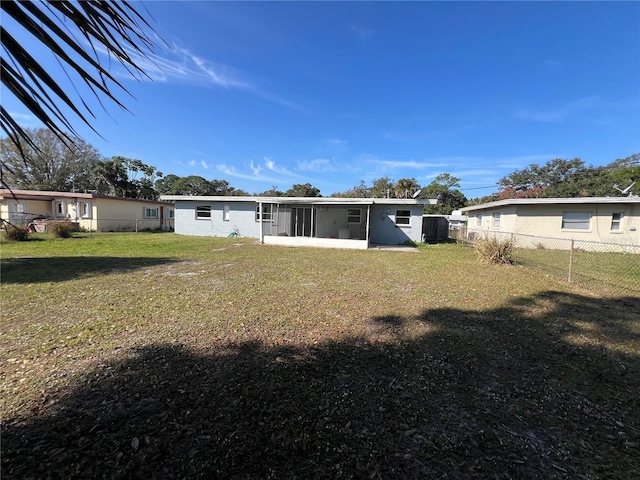 rear view of property featuring a yard and a sunroom