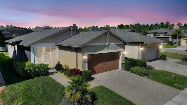 ranch-style home featuring an attached garage, a front yard, decorative driveway, and stucco siding