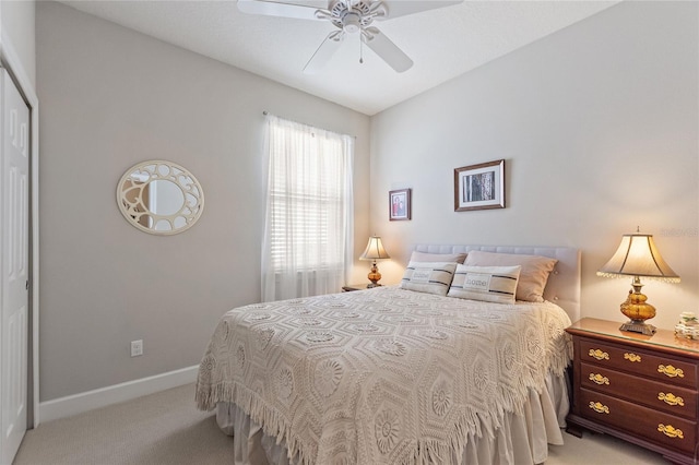 bedroom featuring baseboards, ceiling fan, a closet, and light colored carpet