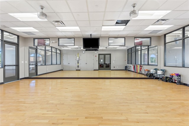 gym with ceiling fan, light wood finished floors, and visible vents