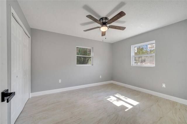 unfurnished bedroom with multiple windows, ceiling fan, a textured ceiling, and a closet