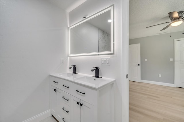 bathroom featuring vanity, wood-type flooring, ceiling fan, and a textured ceiling