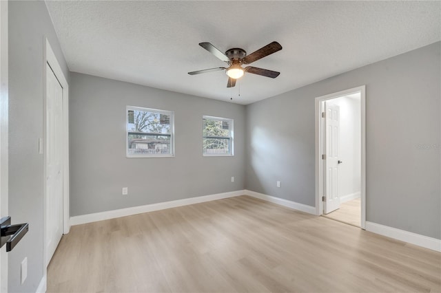 unfurnished bedroom with light hardwood / wood-style flooring, ceiling fan, a textured ceiling, ensuite bath, and a closet