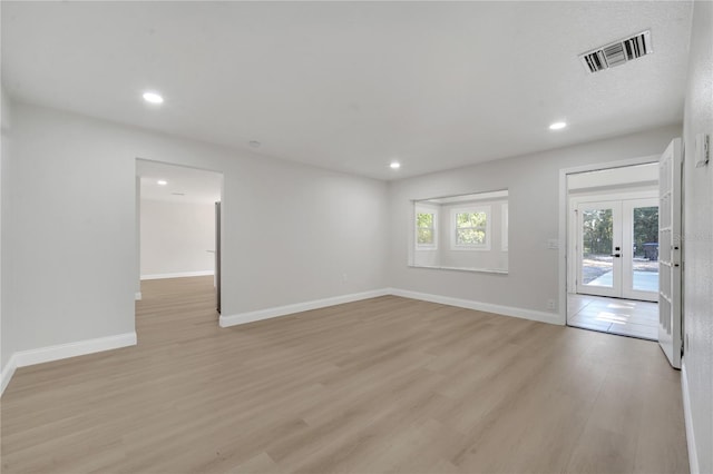 empty room with french doors and light hardwood / wood-style flooring