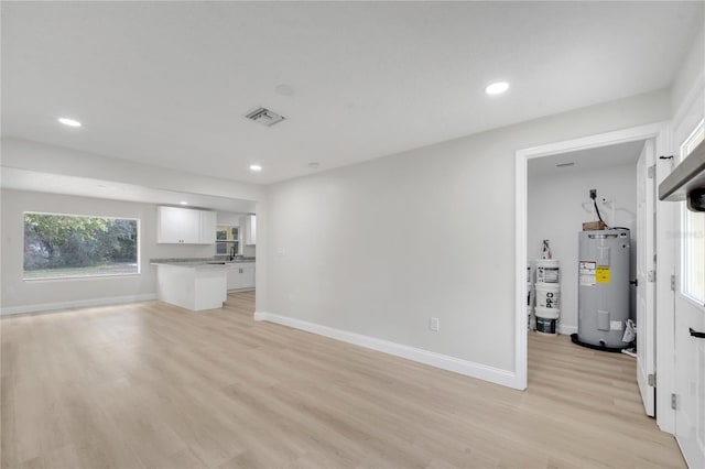 unfurnished living room with water heater, light hardwood / wood-style floors, and electric water heater