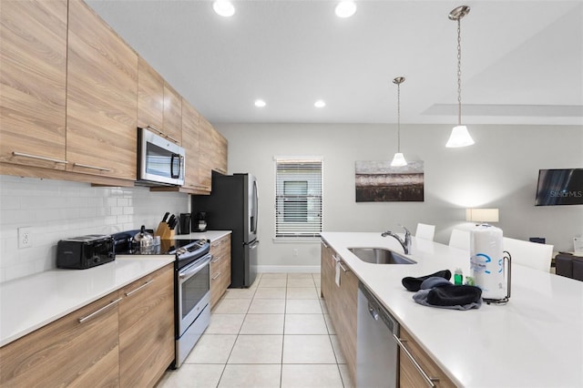 kitchen with light tile patterned floors, appliances with stainless steel finishes, a sink, light countertops, and backsplash