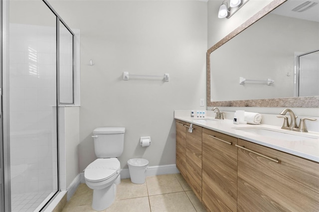 bathroom with a stall shower, a sink, toilet, and tile patterned floors