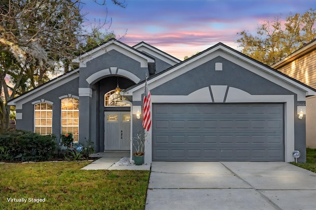 ranch-style house with a garage and a lawn