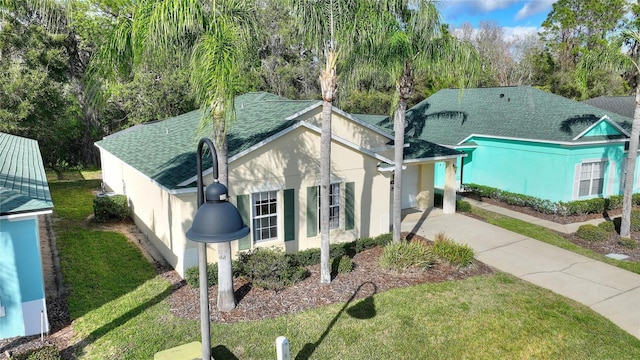 view of front of home featuring a shingled roof, concrete driveway, a front lawn, and stucco siding