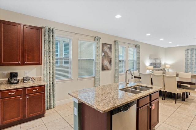 kitchen featuring sink, light stone counters, light tile patterned floors, stainless steel dishwasher, and a kitchen island with sink