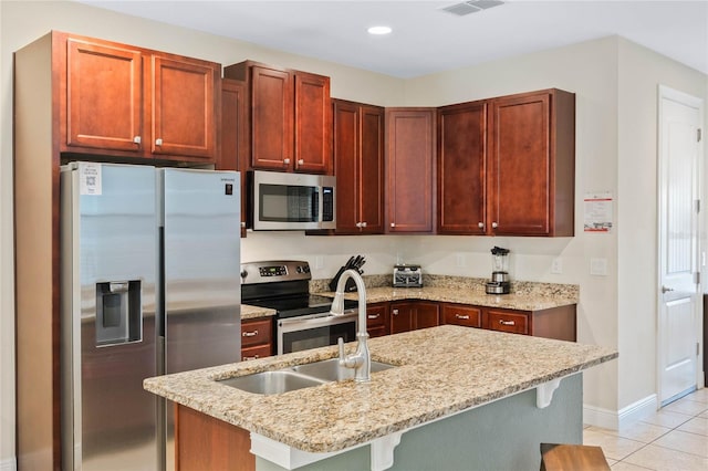 kitchen with light stone countertops, light tile patterned floors, stainless steel appliances, and a breakfast bar