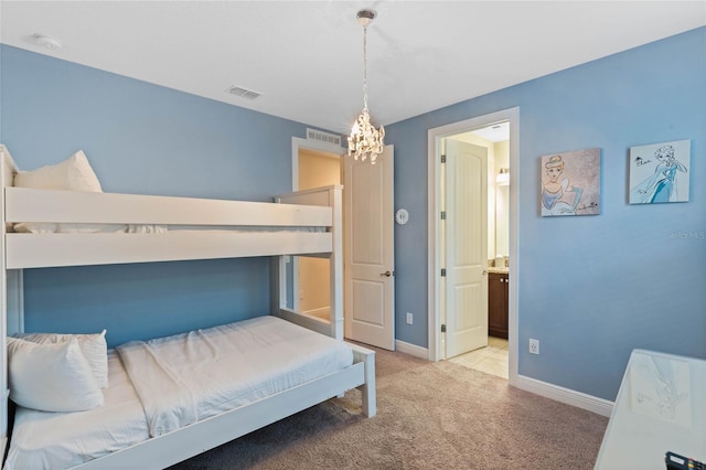 bedroom featuring ensuite bathroom, light carpet, and an inviting chandelier