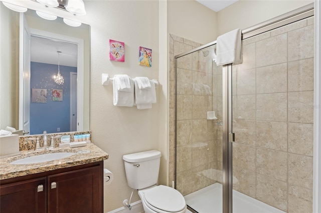 bathroom featuring a shower with door, vanity, a chandelier, and toilet