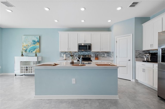 139 Aces High Ln, Davenport, FL 33896 - kitchen with visible vents, a sink, white cabinetry, decorative backsplash, and appliances with stainless steel finishes
