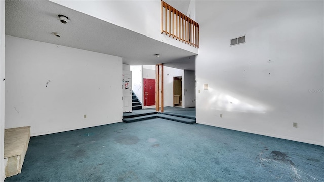 unfurnished living room with a towering ceiling and dark carpet