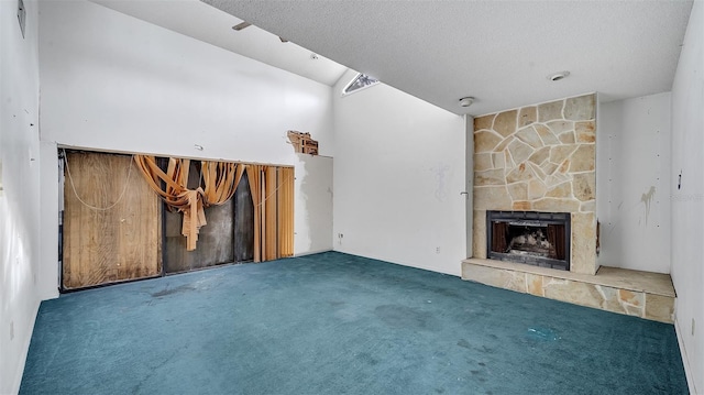 unfurnished living room featuring lofted ceiling, a stone fireplace, dark carpet, and a textured ceiling