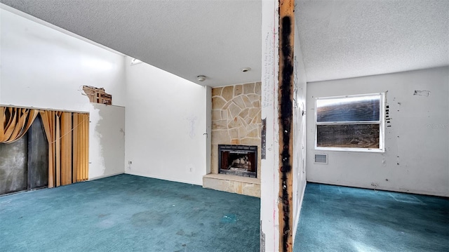 unfurnished living room with a fireplace, a textured ceiling, and dark colored carpet