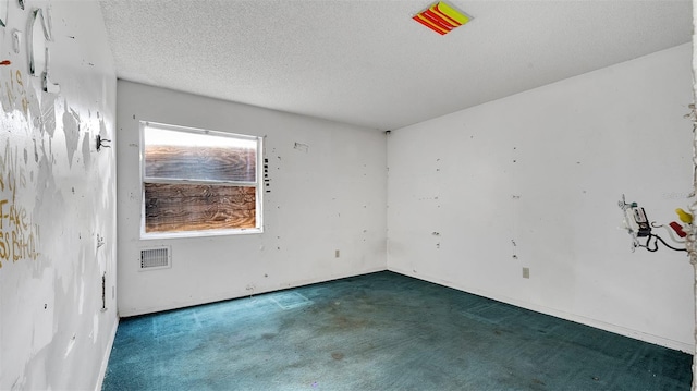 spare room with dark colored carpet and a textured ceiling