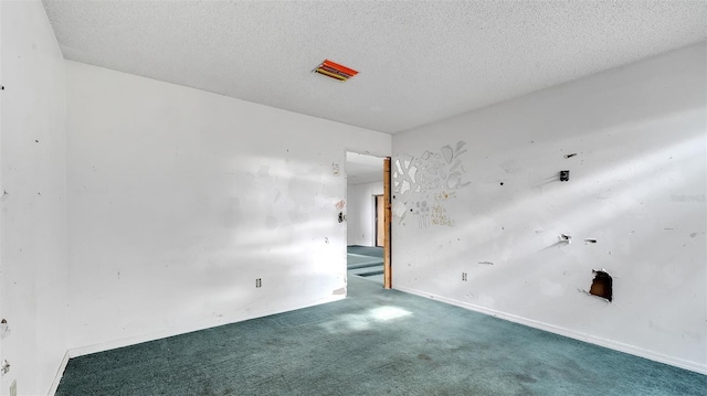 carpeted empty room featuring a textured ceiling