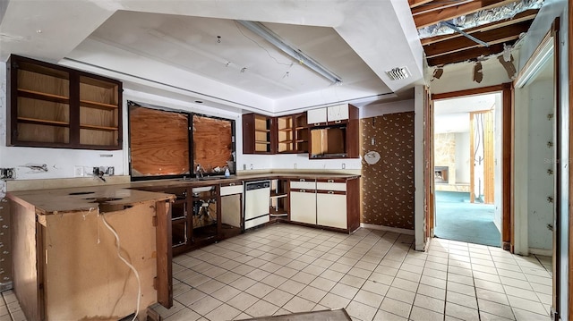 kitchen with light tile patterned flooring, stainless steel dishwasher, a tray ceiling, and sink