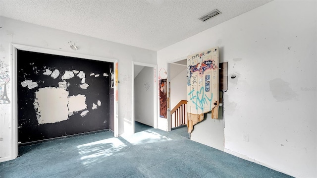 carpeted empty room with a textured ceiling
