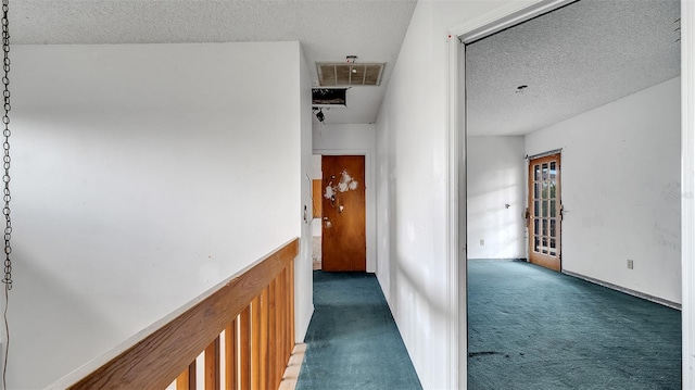 corridor featuring dark carpet and a textured ceiling
