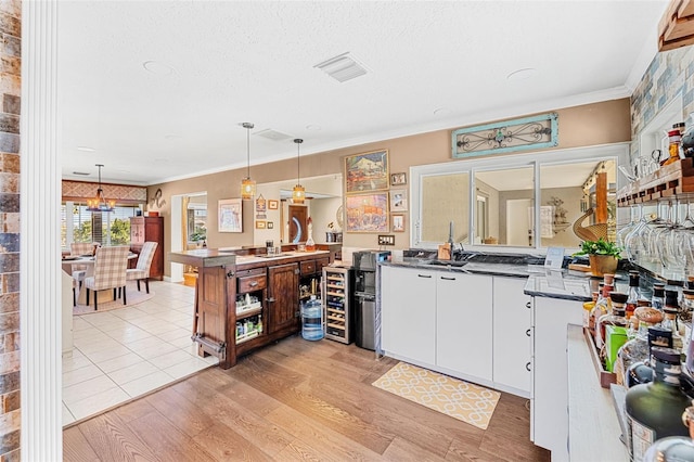 kitchen featuring hanging light fixtures, ornamental molding, white cabinets, and light hardwood / wood-style floors