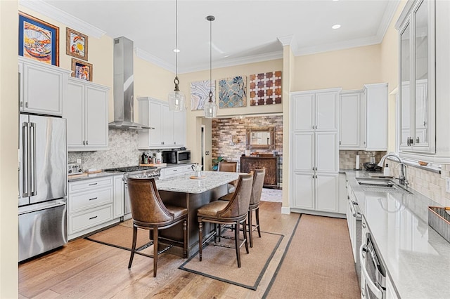 kitchen with wall chimney exhaust hood, white cabinetry, decorative light fixtures, high quality appliances, and a kitchen breakfast bar