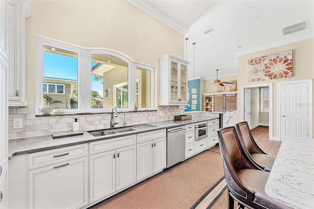 kitchen with sink, tasteful backsplash, ornamental molding, stainless steel appliances, and white cabinets