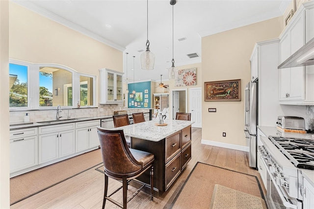 kitchen with sink, a breakfast bar, white cabinetry, hanging light fixtures, and a center island