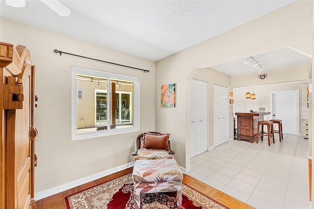 living area featuring light hardwood / wood-style flooring, rail lighting, and a textured ceiling