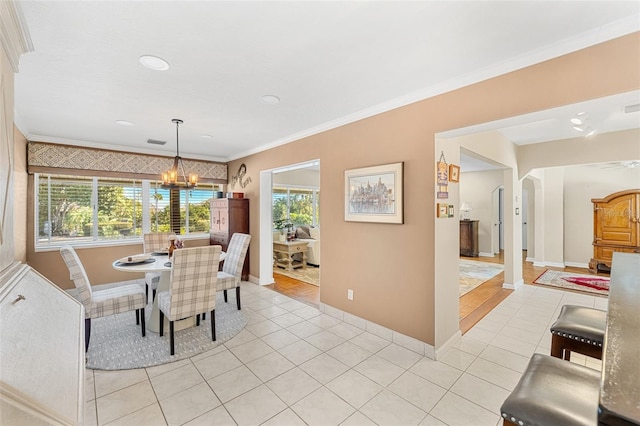 tiled dining area with ornamental molding, a healthy amount of sunlight, and an inviting chandelier