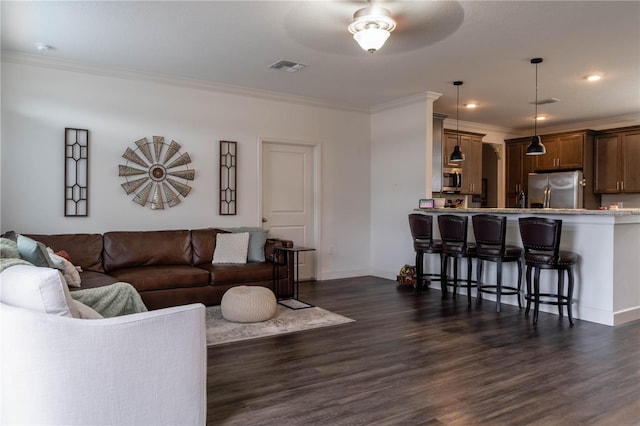 living room with ornamental molding, dark wood-type flooring, and ceiling fan