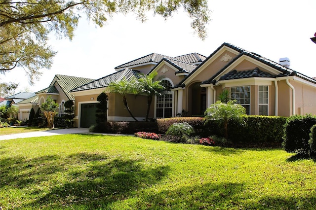 mediterranean / spanish house featuring a garage and a front yard