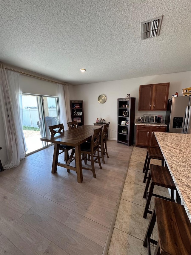 dining space with light hardwood / wood-style floors and a textured ceiling