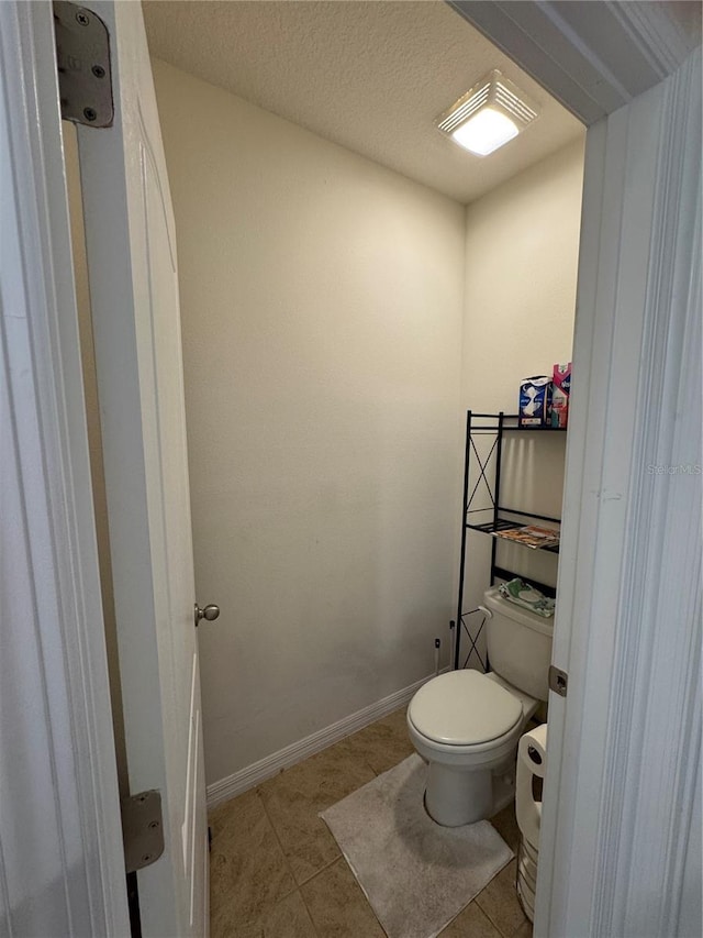 bathroom featuring toilet, tile patterned flooring, and a textured ceiling