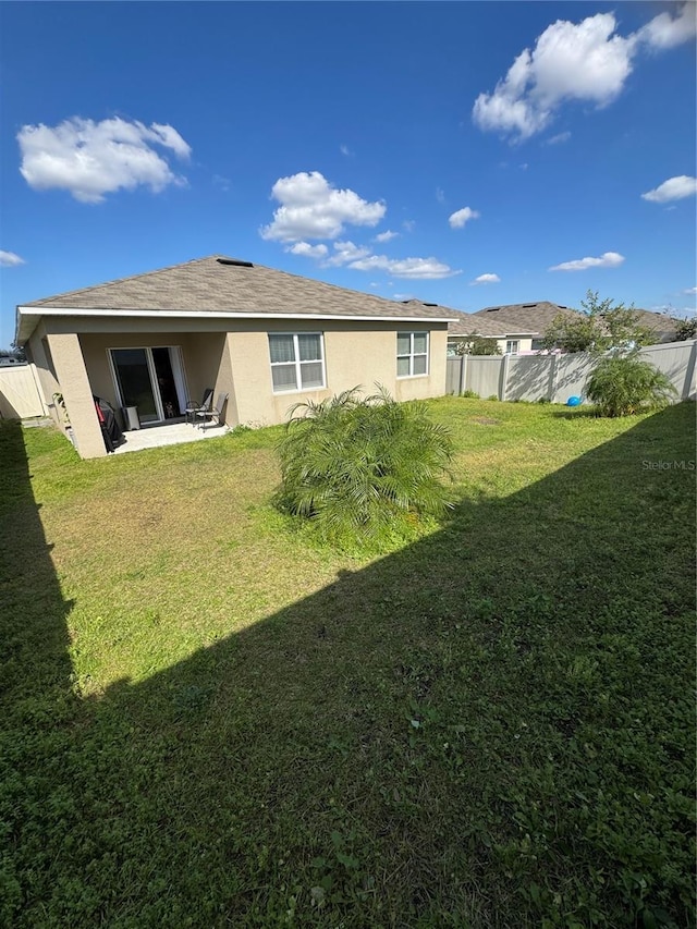 back of property with a yard and a patio