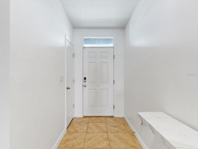 entryway with a textured ceiling, baseboards, and light tile patterned floors