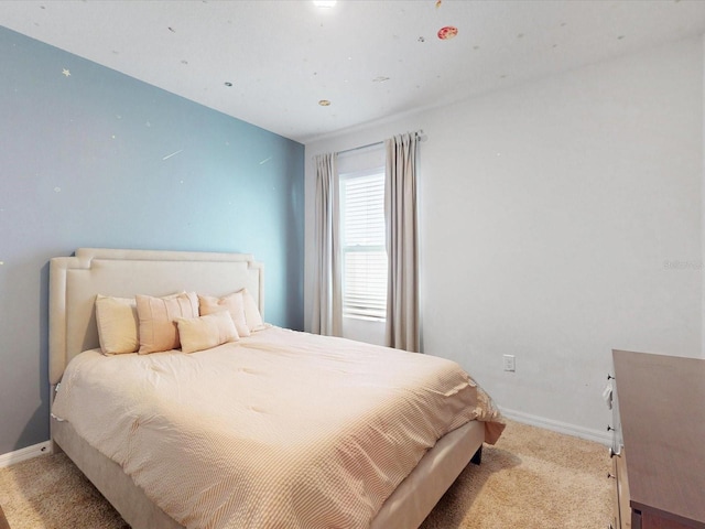 bedroom with light colored carpet and baseboards