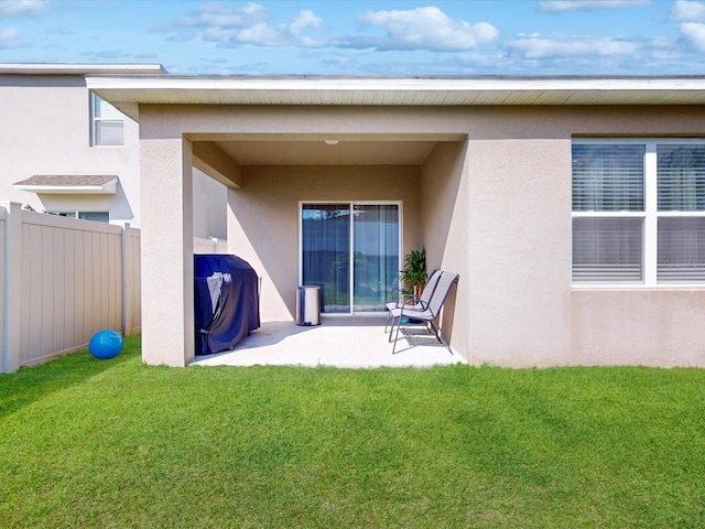 exterior space featuring a patio area, fence, a lawn, and stucco siding