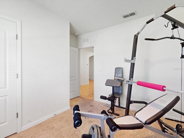 exercise room with arched walkways, baseboards, visible vents, and light colored carpet