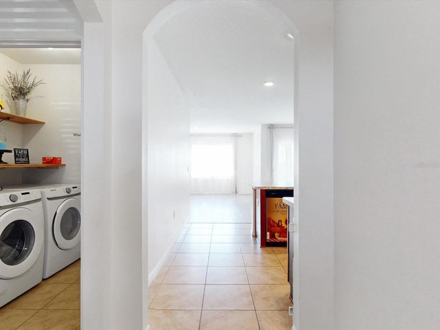 laundry area with washing machine and dryer, laundry area, light tile patterned flooring, and arched walkways