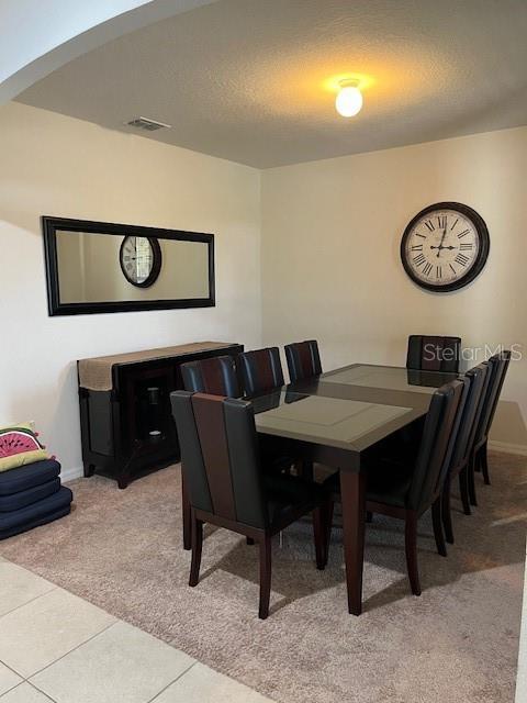 dining room with light carpet and a textured ceiling